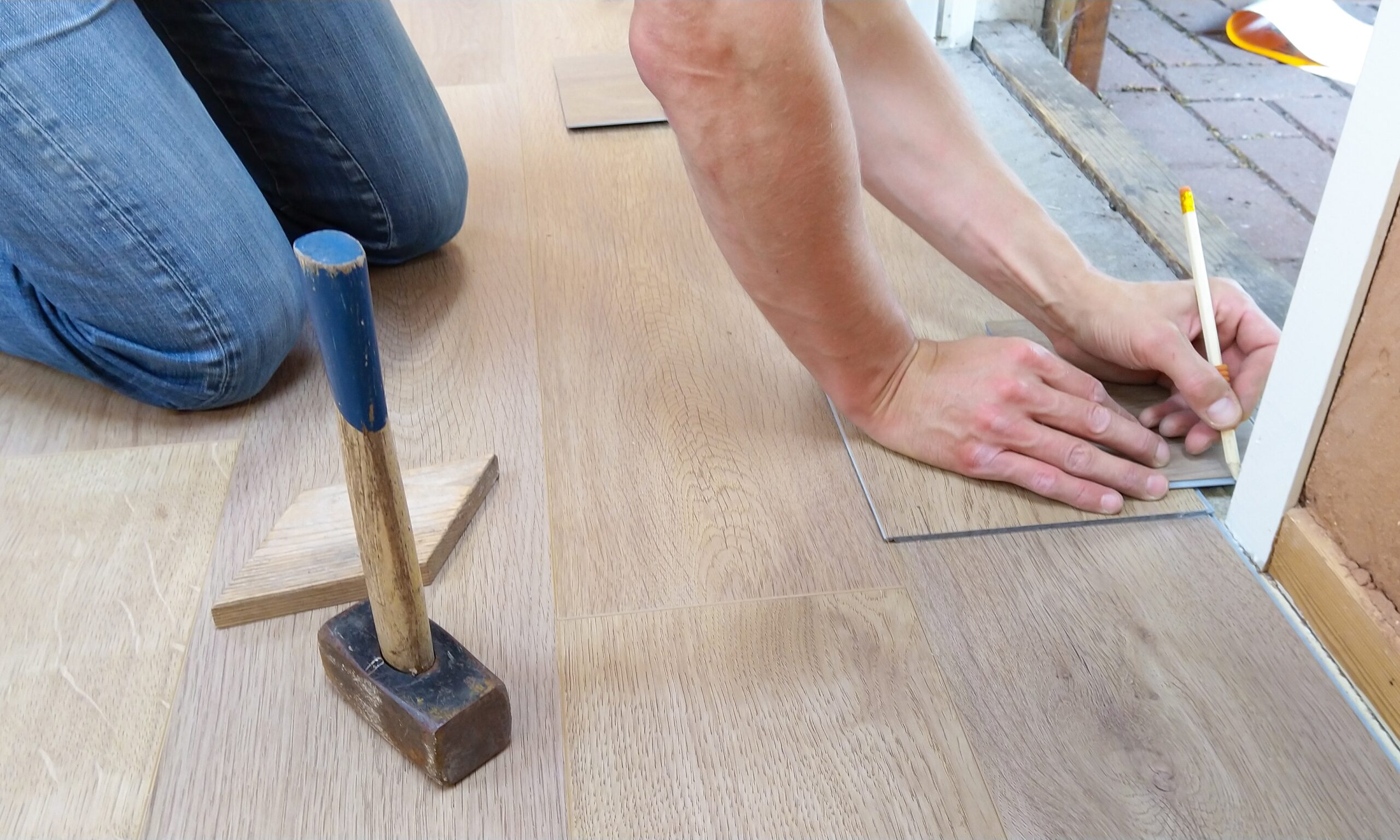 A person holding a pencil while installing vinyl floors
